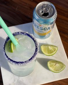 a drink and some limes on a table