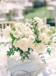 a table with white flowers and greenery on it