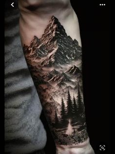 a man's arm with a mountain and forest tattoo on the left side of his arm