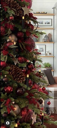 a christmas tree decorated with red and gold ornaments, pine cones, candles and other holiday decorations