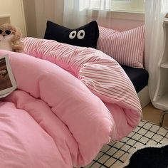 a bed with pink comforter and pillows on it