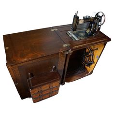 an old fashioned sewing machine sitting on top of a wooden table with drawers underneath it