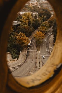 an aerial view of a city street through a round window with trees and buildings in the background