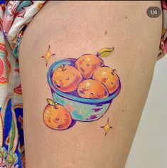 a woman's thigh with an image of oranges in a bowl on it