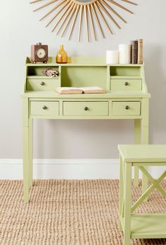 a green desk and chair in front of a wall with a sunburst above it