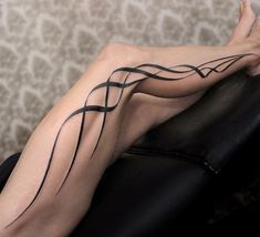 a woman's legs with black lines painted on them and her bare body sitting on a couch