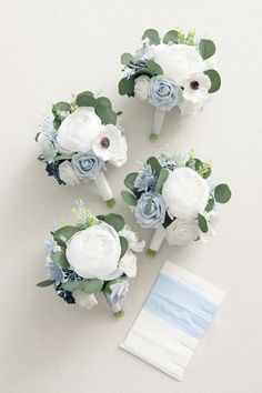 three bridal bouquets with blue and white flowers on them next to an envelope