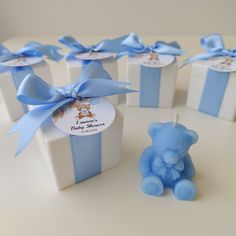 a small blue teddy bear sitting in front of some gift boxes