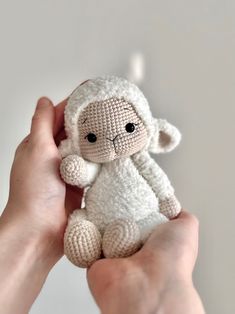 a hand holding a small white stuffed animal