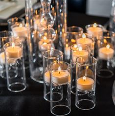 many candles are lit in clear glass vases