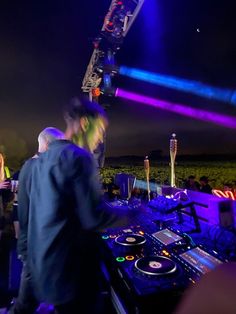 two djs are playing music at an outdoor event with bright lights in the background