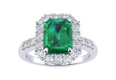 an emerald and diamond ring set in white gold with diamonds around the band, on a white background