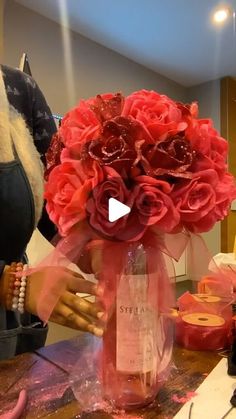 a vase filled with red roses on top of a table next to other bottles and candles