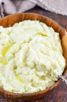 a wooden bowl filled with mashed potatoes on top of a table