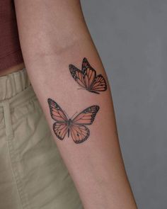 two butterflies on the left arm, one is orange and the other is black in color