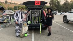 two people dressed up in costumes standing next to a car with the back door open