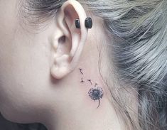 a woman's ear with a dandelion tattoo