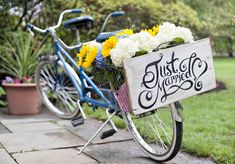 a blue bicycle with flowers in the basket parked next to another bike that has just been decorated