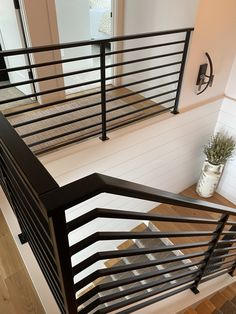 the stairs are made of wood and have metal railings on each handrail, along with a potted plant