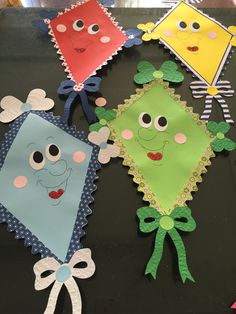 four kites made out of paper with faces and bows on the sides, sitting on a table