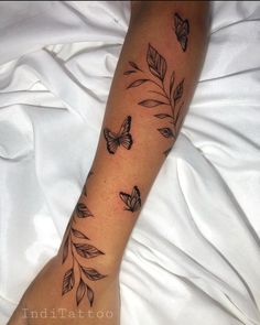 a woman's leg with butterflies on it and leaves in the foregrounds