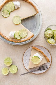 a slice of key lime pie on a plate with lemons and lime slices around it