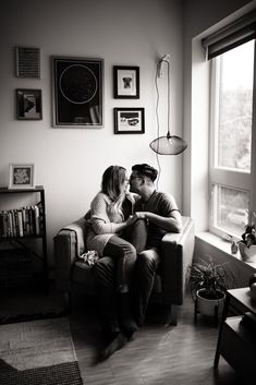 a man and woman sitting next to each other on a couch in front of a window