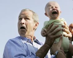 a man holding a baby up to his face with an angry look on his face