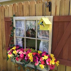 a window box filled with colorful flowers next to a wooden fenced in shed area