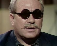 an older man wearing sunglasses and a mustache