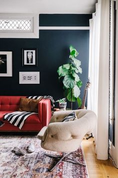 a living room with a red couch, chair and guitar on the floor in it