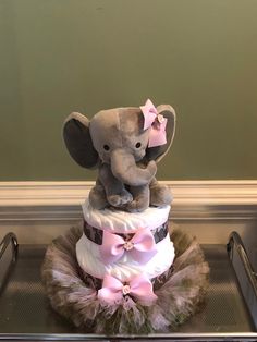 a baby elephant sitting on top of a diaper cake with pink bows and tulle