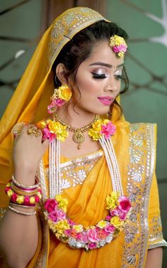 a woman wearing a yellow sari with flowers in her hair and jewelry on her head