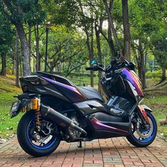 a motorcycle parked on the side of a brick road in front of trees and grass