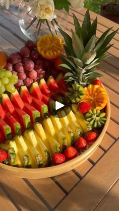 a wooden table topped with a bowl filled with fruit and veggie platters