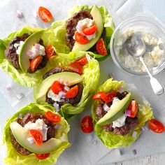 several lettuce cups filled with meat and veggies next to a bowl of dip