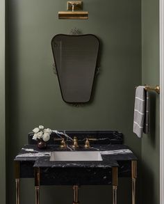 a bathroom with green walls and marble counter top, gold faucets and brass fixtures