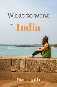 a woman sitting on top of a stone wall next to the ocean with text overlay that reads, what to wear in india practical guide