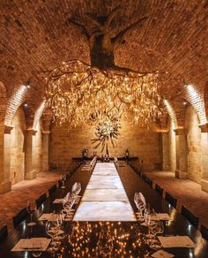 a long table is set up in an old brick room with chandeliers hanging from the ceiling