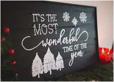 a wooden sign that says it's the most wonderful time of the year next to a christmas tree