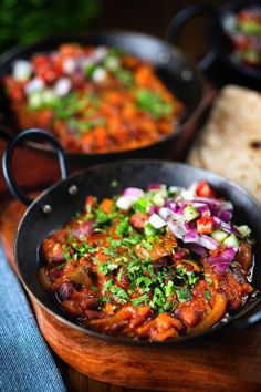 two pans filled with food sitting on top of a wooden table next to each other