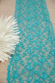 a white flower sitting on top of a table next to a piece of blue lace