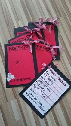 three pieces of red paper with black and white writing on them sitting on a wooden floor