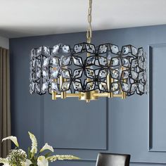 a chandelier hanging over a dining table in a room with blue walls and black chairs