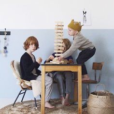 two children playing with wooden blocks on a table in front of a blue painted wall