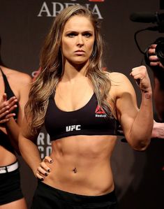 a female fighter posing for the camera with two men behind her and another man standing next to her