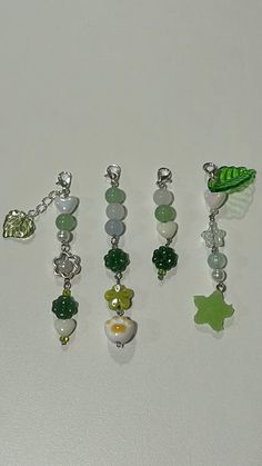 several charms are arranged on a white surface with one being a green leaf and the other is a ladybug