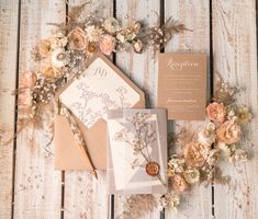 the wedding stationery is laid out on top of an old wooden table with dried flowers