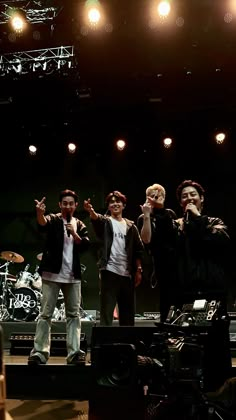 group of young men standing on stage with their hands in the air