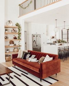 a living room filled with furniture and a stair case in front of a kitchen area